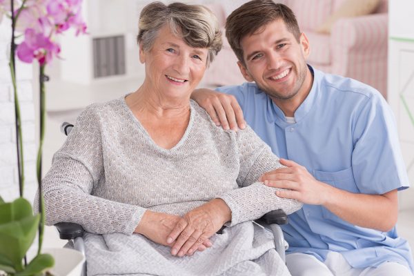 smiling-carer-with-senior-in-rest-home-PC34NGJ